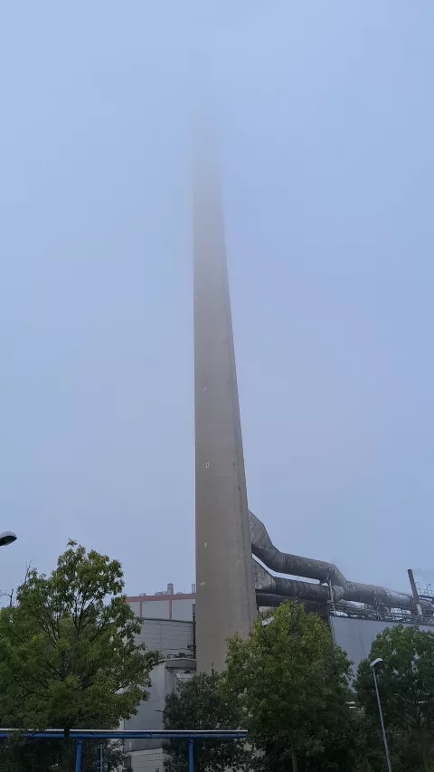 La ch3minée de cette usine a la tête dans les nuages
